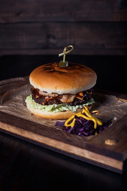 Cheeseburger op een houten dienblad in een restaurant, op een donkere achtergrond.