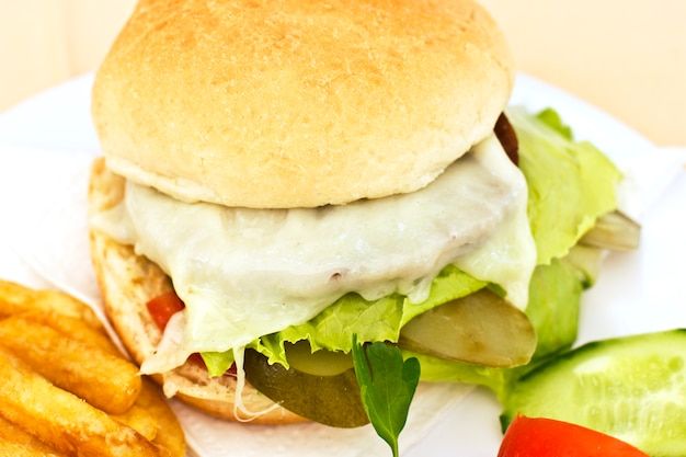 Cheeseburger with French fries, sliced cucumbers and tomatoes