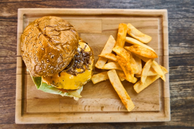 フライドポテトと木製のテーブルの上のチーズバーガー