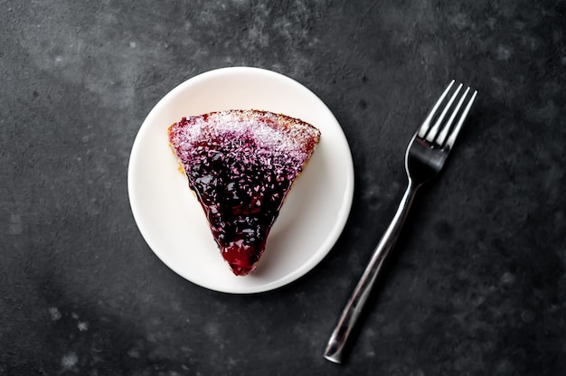 Cheesecake - cake met bes op een witte plaat en koffie op een stenen achtergrond met kopie ruimte voor uw tekst