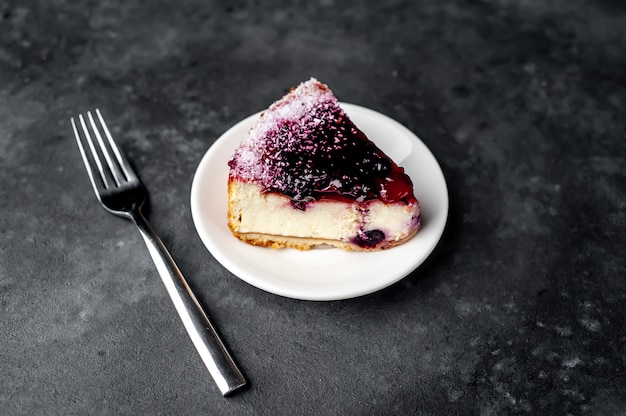 Cheesecake - cake met bes op een witte plaat en koffie op een stenen achtergrond met kopie ruimte voor uw tekst