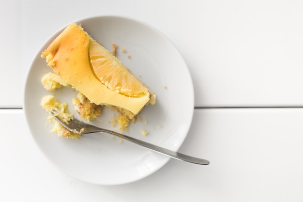 Photo cheesecake eaten with a fork on a white plate