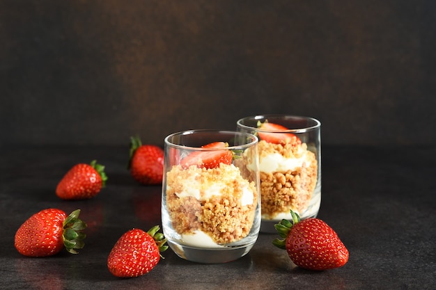 Cheesecake in a glass with strawberries on a dark concrete background. Dessert in a glass.