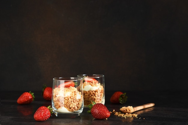 Cheesecake in a glass with strawberries on a dark concrete background. Dessert in a glass.