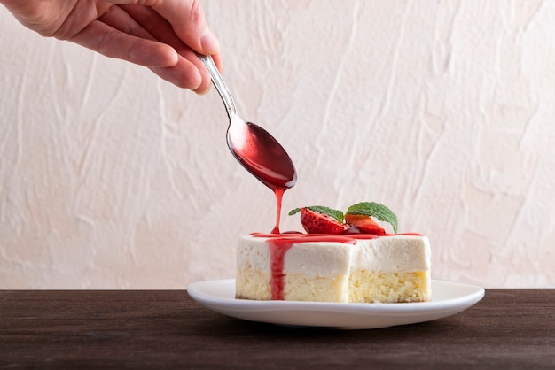 Cheesecake is poured over with berry syrup. Delicate dessert garnished with fresh strawberries.