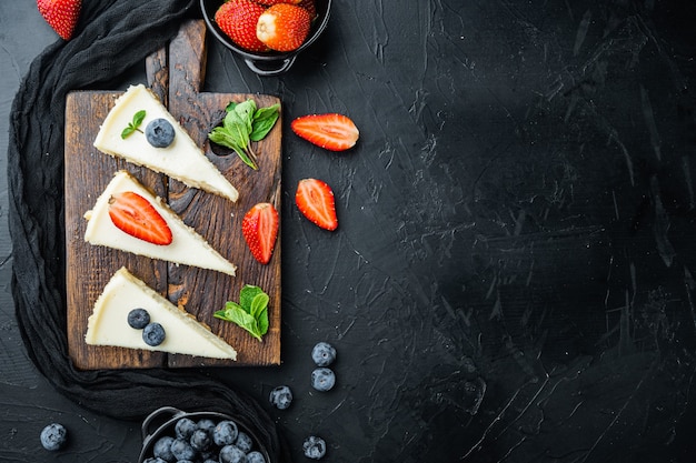 Cheesecake met bosbessen en aardbeien, op zwarte tafel, bovenaanzicht plat lag