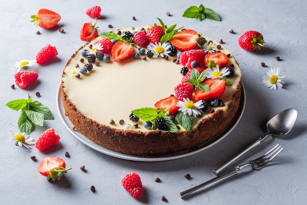 Cheesecake pie with fresh berries strawberries blueberries and blackberries and mint chamomiles