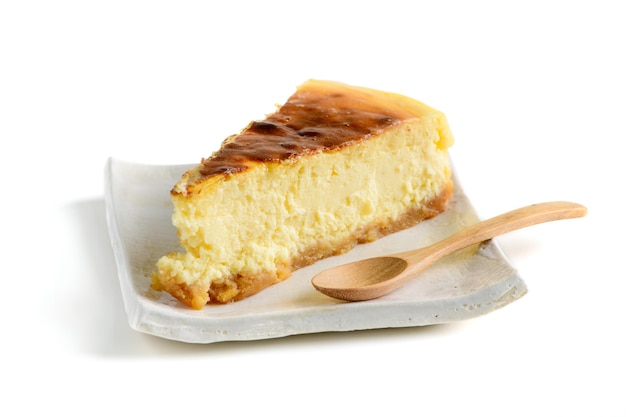 Cheesecake slice Slice of tasty cake on white plate and wood spoon isolated