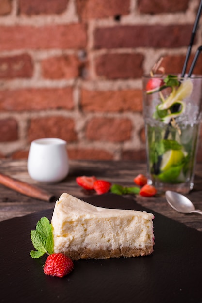 Cheesecake and strawberry on a stone plate on rustic wood table