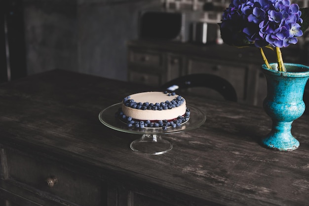 Cheesecake with blueberries on glass stand on wooden table