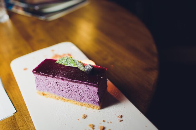 Cheesecake with chocolate sauce and cup of coffee Hands holding slice of chocolate cake on plate