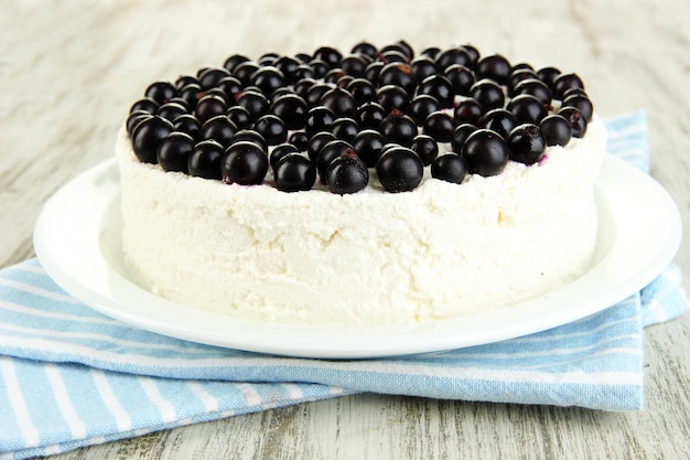 Cheesecake with fresh berries on white plate on wooden table closeup