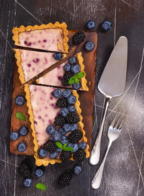 Cheesecake with fresh blackberries blueberries and mint on a gray stone background