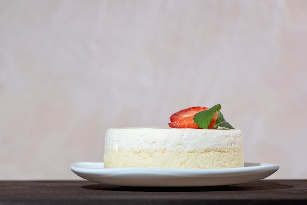 Cheesecake with fresh strawberries and mint on white dish. Delicate cheese dessert.