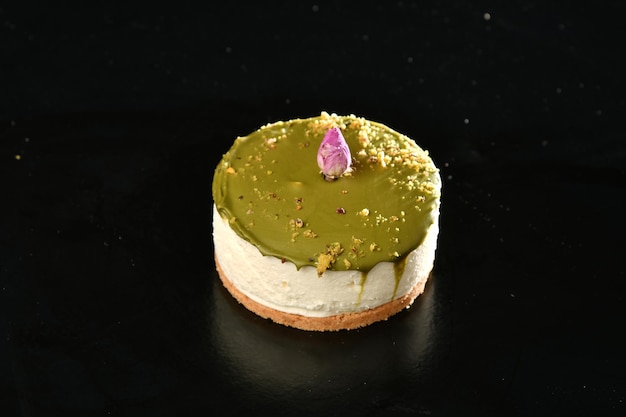 Photo a cheesecake with green cream and a flower on top