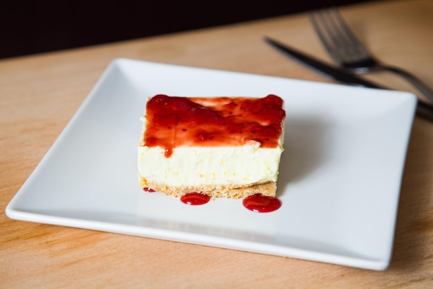 Foto cheesecake con salsa ai frutti rossi e frutta fresca come lamponi, mirtilli o fragole.