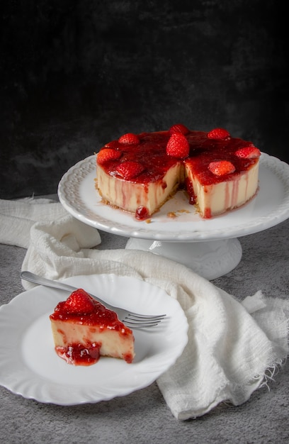 Cheesecake with strawberry sauce topping on white support with gray background.