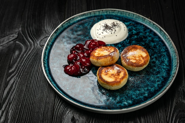 Cheesecakes met zure room cherry jam op een donkere houten tafel