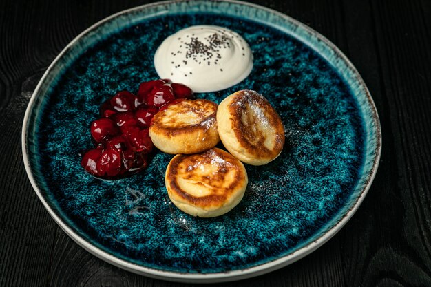 Cheesecakes met zure room cherry jam op een donkere houten tafel