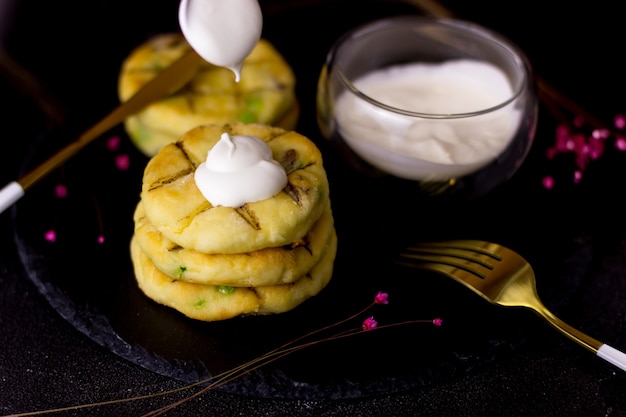 Cheesecakes on a plate of slate on a black background. Cheesecakes with pouring sour cream