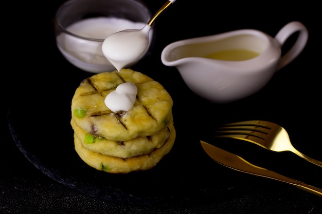 Torte di formaggio su un piatto di ardesia su sfondo nero. cheesecake con versamento di panna acida