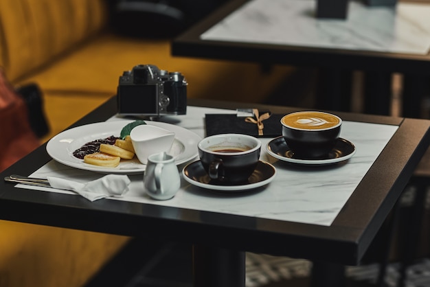 Cheesecakes voor het ontbijt met jam, cappuccino en espresso en camera. banner voor cafés en restaurants