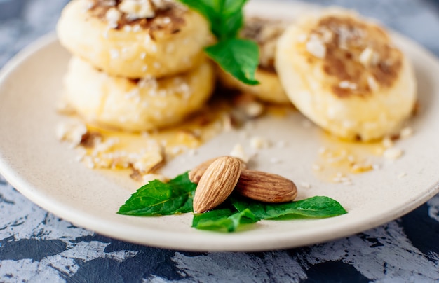 Cheesecakes con mandorle fresche alla menta e sciroppo d'acero su uno sfondo grigio da un tavolo di cemento.