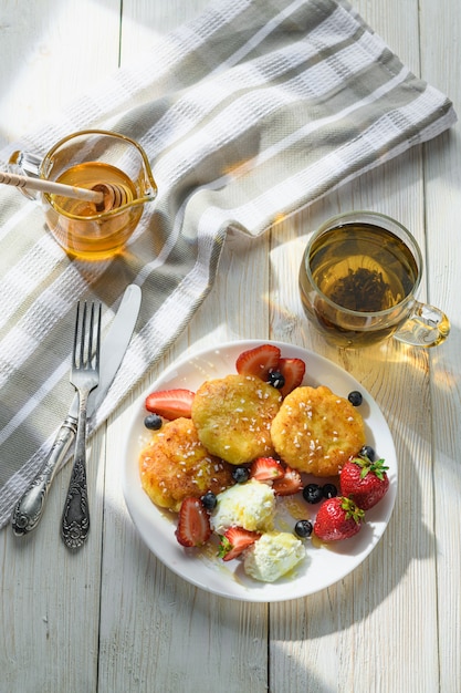 cheesecakes with honey tea and berries on a wooden table