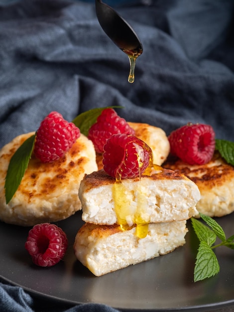 Cheesecakes with mint, raspberries, honey. Ukrainian, Russian cuisine breakfast meal. Homemade food.