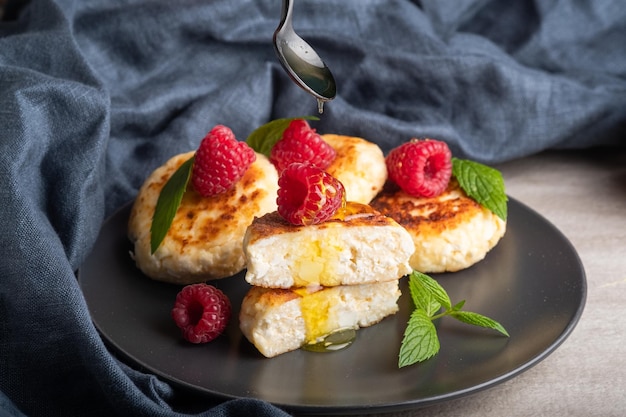 Cheesecakes with mint, raspberries, honey. Ukrainian, Russian cuisine breakfast meal. Homemade food.