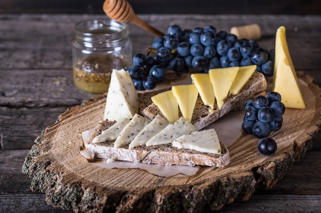 Formaggi con uva, pane, miele. formaggio di capra, erbe aperitivo. bruschetta con formaggio