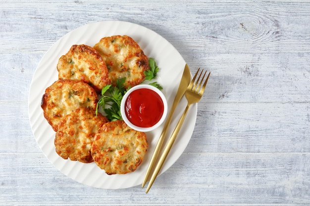 Cheesy Chicken Fritters Kipfilet pasteitjes geserveerd met tomatensaus op een witte plaat horizontale weergave van boven plat lag vrije ruimte