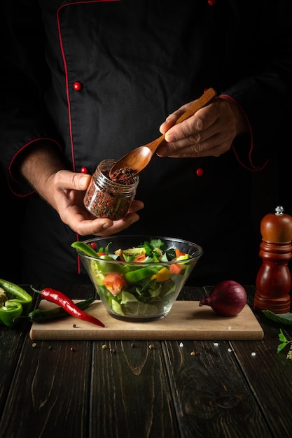 The chef adds flavoring to the vegetable salad Vegetarian food by hands of the cook in the kitchen