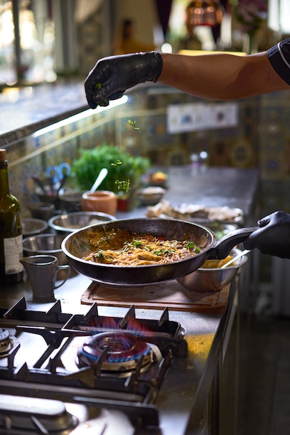 요리사는 토마토와 굴을 냄비에 신선한 채소를 넣습니다.