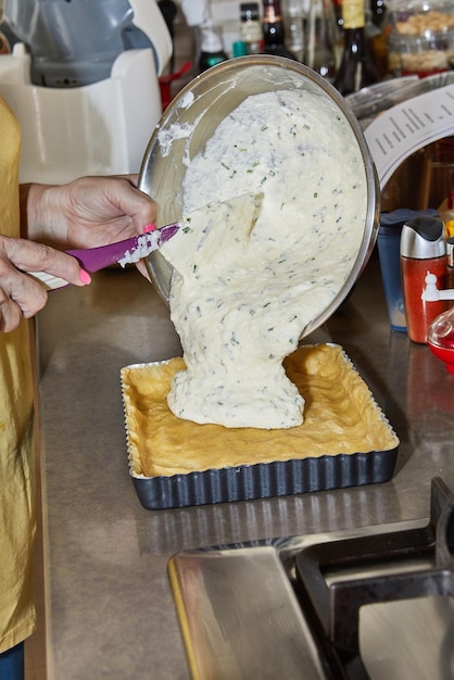 Chef adds pie dressing to the pie dough in a metal mold