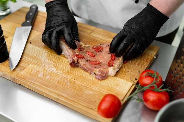 The chef adds salt with his hands and marinates the raw meat before grilling it. Restaurant service food concept.