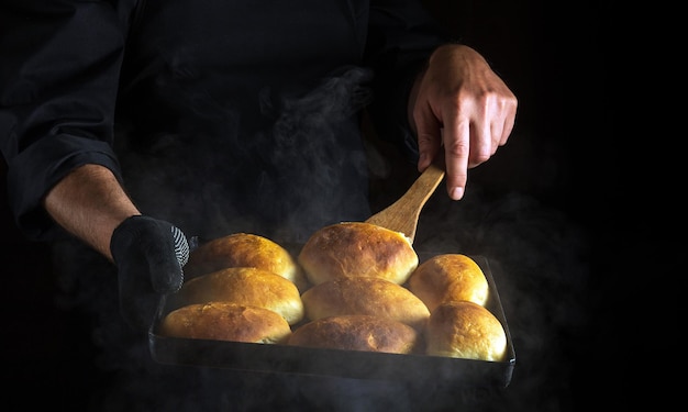 Chef or baker flips the pies on a hot baking sheet The concept of making hamburger buns Black space for menu or recipe