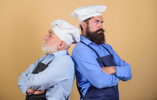 Chef battle who is the best family dinner father and son cooking together commercial kitchen at restaurant professional chefs serious men in cook hat mature bearded chef