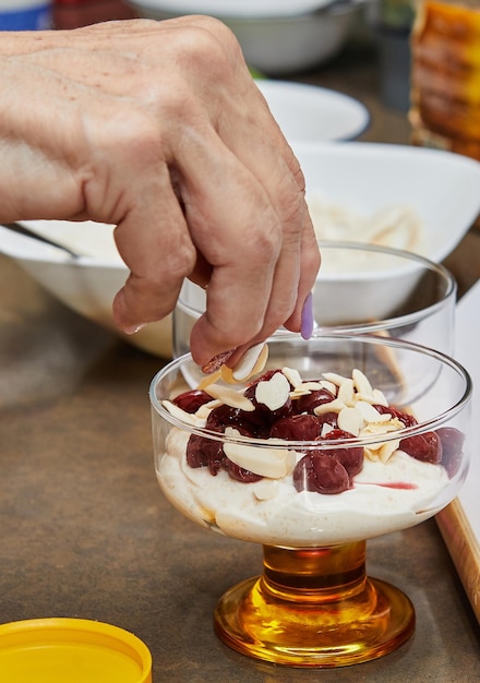 Chef bereidt een speciaal dessert voor met verse room kersenkoekjes en noten in een glas