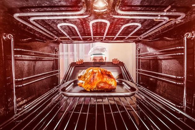 Chef bereidt gebraden kip in de oven, uitzicht vanaf de binnenkant van de oven. Koken in de oven.