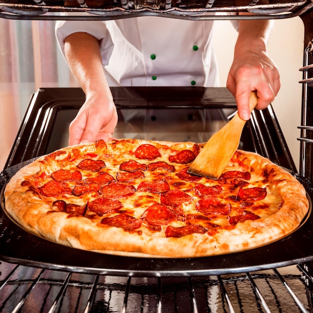 Chef bereidt pepperoni pizza in de oven, uitzicht vanaf de binnenkant van de oven. Koken in de oven.