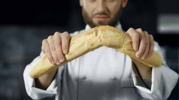 Foto chef rompendo il pane francese al rallentatore mani del fornaio del primo piano che spezzano il pane