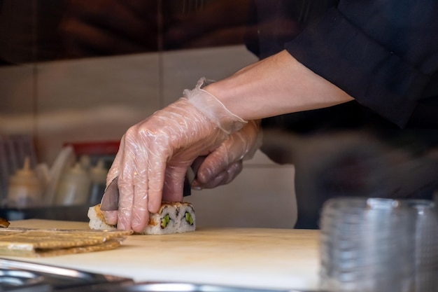 The chef brushes the rolls with teriyaki sauce