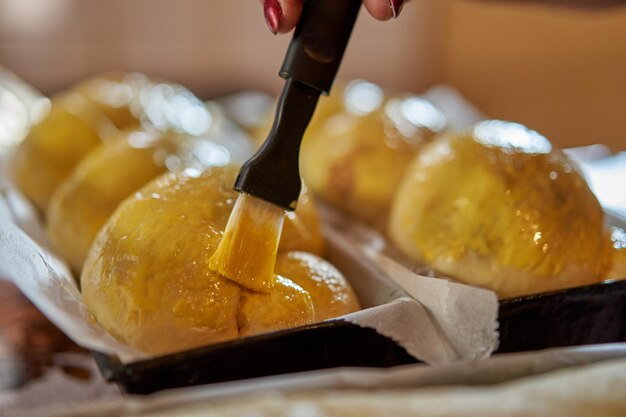 Chef brushing the cakes in the trays with egg yolk