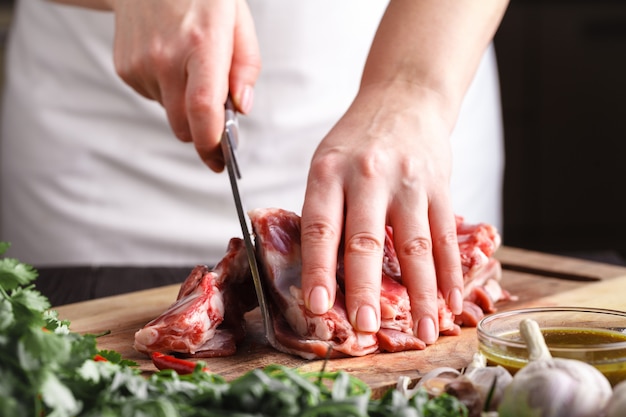 シェフの肉屋がラム肉をナイフで切る