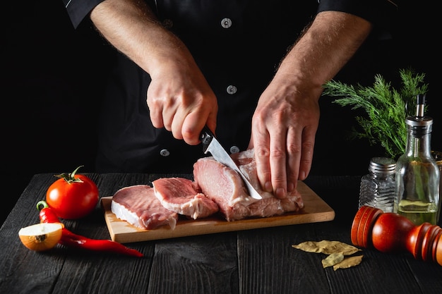 Chef Butcher cutting pork meat with knife on kitchen, cooking food