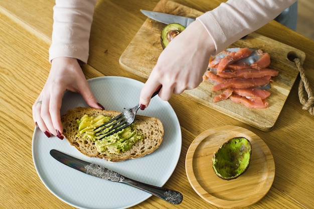 Lo chef butters avocado su pane tostato di pane nero.