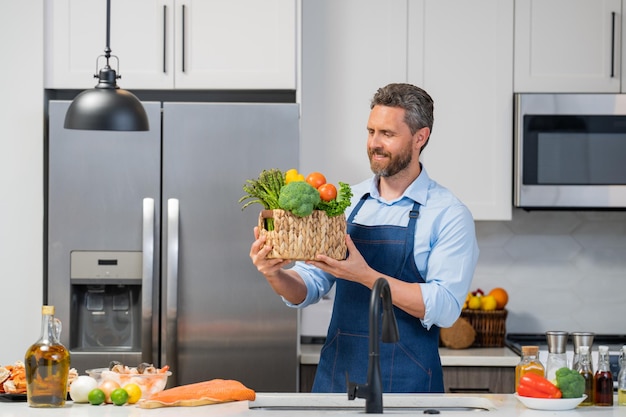 Chef in cook apron cooking in kitchen man on kitchen with vegetables portrait of casual man cooking