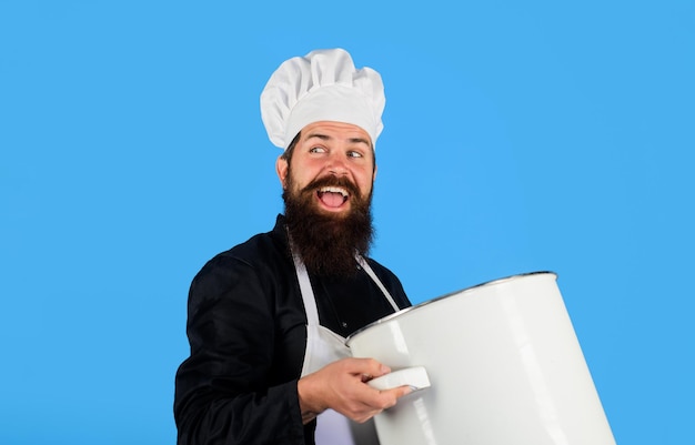 Chef cook or baker with saucepan in hand chef in uniform\
cooking with casserole professional chef in