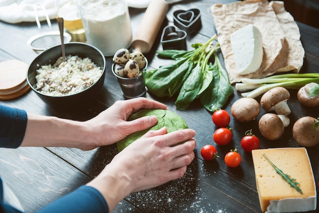 Lo chef cuoco passo dopo passo prepara i ravioli verdi a forma di cuore per una cena festiva